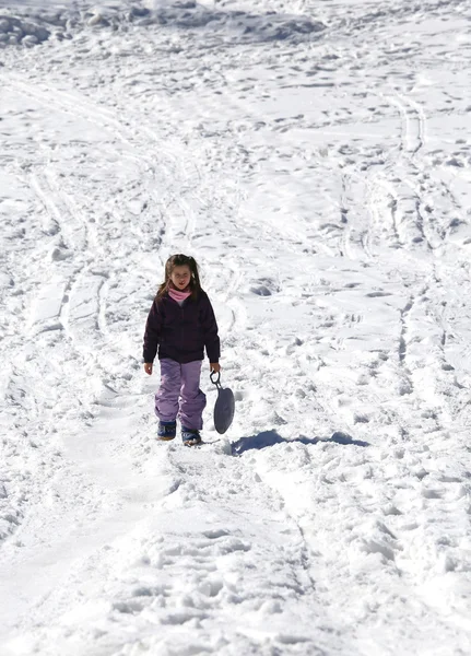 Fetița se joacă cu sania în timpul iernii pe zăpada albă — Fotografie, imagine de stoc