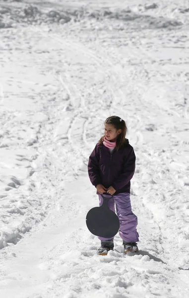 Fetița se joacă cu sania în timpul iernii pe zăpadă — Fotografie, imagine de stoc