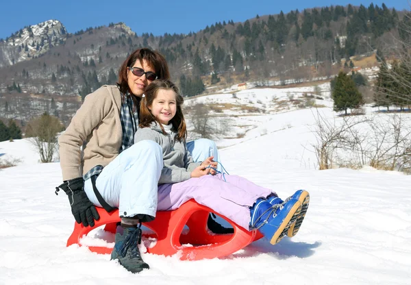 Mamma och liten flicka i berget på släde — Stockfoto