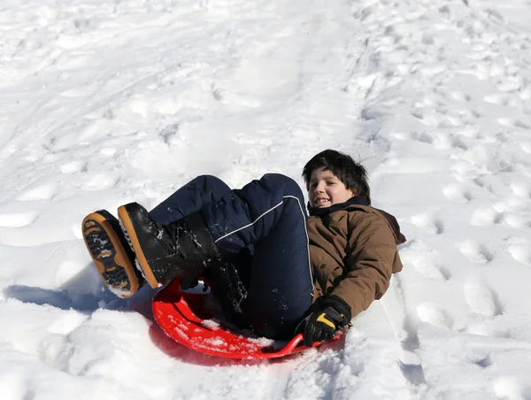 男孩玩雪橇在冬天洁白的雪地上 — 图库照片