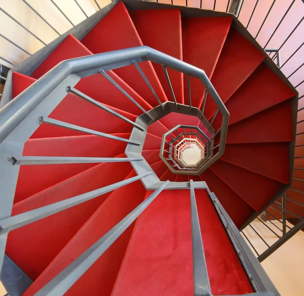 Спиральная лестница с красной ковровой дорожкой в современном здании — стоковое фото