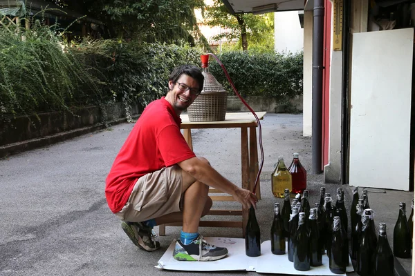 Young man smiling while bottling the wine at home — Stock Photo, Image