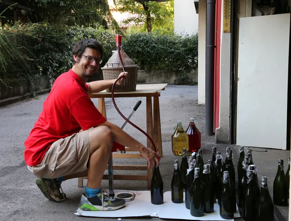 Jeune homme souriant en embouteillant le vin à la maison — Photo