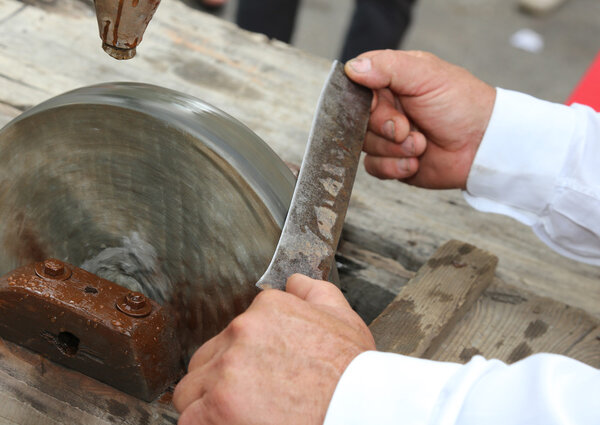 Elder while sharpening the blade of the knife on the large water