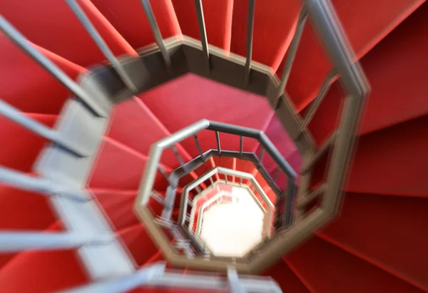 Спиральная лестница с движущимися ступенями и красной дорожкой — стоковое фото