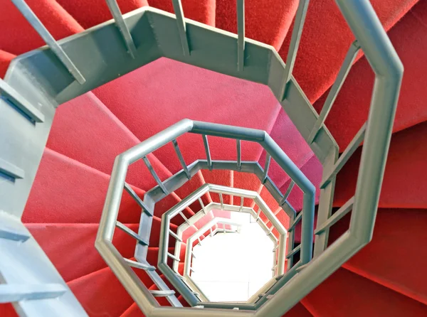 Lange schmiedeeiserne Wendeltreppe mit rotem Teppich — Stockfoto