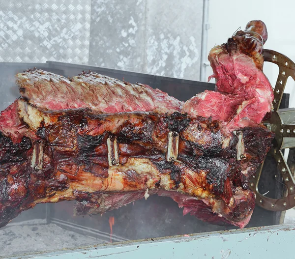 Huge Bull spit-cooked skewered in the mechanized Rotisserie — Stock Photo, Image