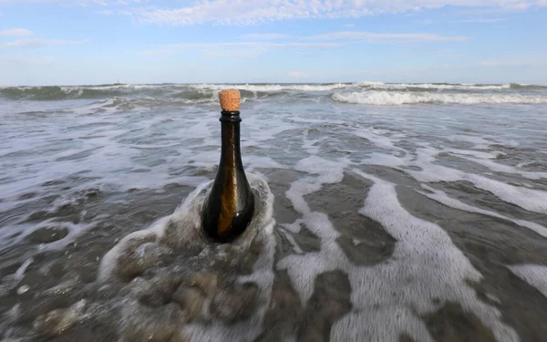 Okyanus gelgitinin üzerinde mantar tıpası olan siyah cam şişe içinde gizli bir mesaj tutuyor.