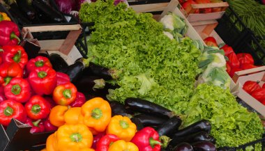 Satıcılarda satılan sayısız kutu renkli dolma biber olgun patlıcanlar ve yapraklı yeşillikler sergileniyor.