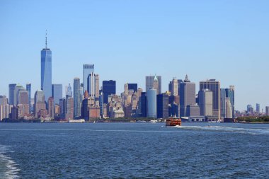 Manhattan ufuk çizgisi ve turuncu feribot New York adasına doğru ilerliyor.
