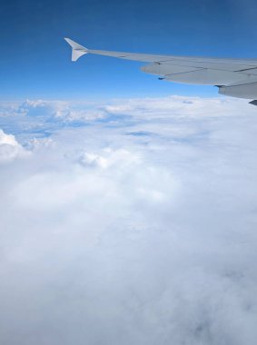 Uçak kanatları okyanusun üzerinde uçuyor. Beyaz bulutlar 40 bin fitin üzerinde.