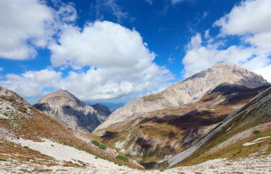 wide panoramic view of rocky mountain peaks and rugged terrain in the abruzzo region of central italy under a dramatic cloudy blue sky