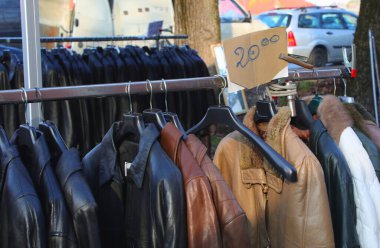 çeşitli kullanılmış ceketler ve askılarda asılı diğer giysi eşyalar açık hava bit pazarı veya ikinci el satış