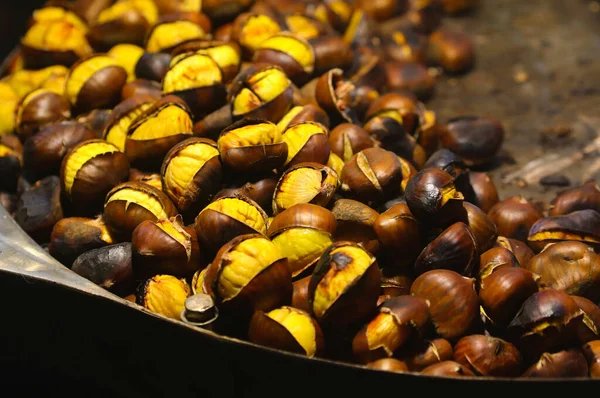 Yakın plan görüntüsü taze kavrulmuş ve soyulmuş kestaneler yığılmış metal yemek tepsisi veya karanlık arka plana karşı konteynır