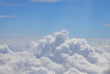 Beyaz kabarık bulutlar ve yukarıdaki mavi gökyüzü uçuş sırasında 40 bin feet yükseklikteki bir uçaktan görüldü.