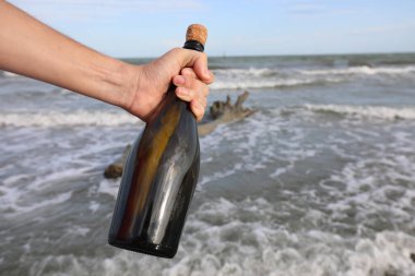 Bulanlar, içinde okyanus tarafından keşfedilmiş şifreli bir not bulunan cam kabı tutuyorlar.