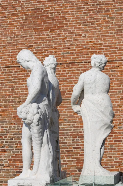 Estátuas antigas com o fundo parede de tijolo vermelho — Fotografia de Stock