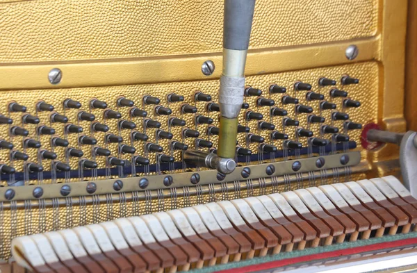 Afinador dentro de un piano con pequeño martillo — Foto de Stock