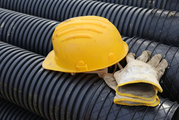 Hard hat and work gloves in construction site — Stock Photo, Image