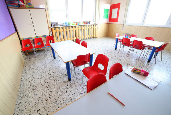 nursery classroom with school desks and small red chairs