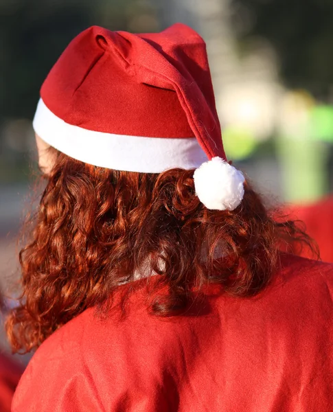 Chica con el pelo rojo con una gorra roja en la cabeza vestido como Santa — Foto de Stock