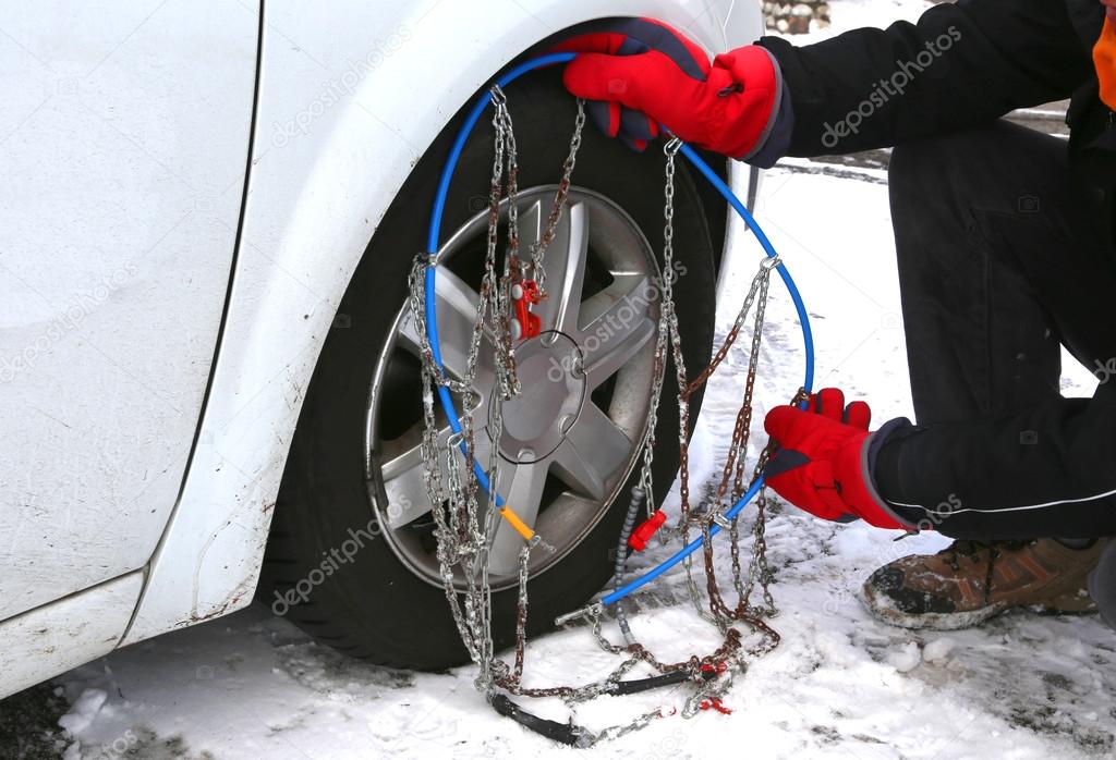 man with red gloves install snow chains in the car tyre