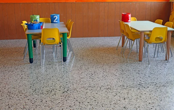 Schreibtisch einer Kindertagesstätte mit nummerierten Krügen und kleinen gelben Stühlen — Stockfoto