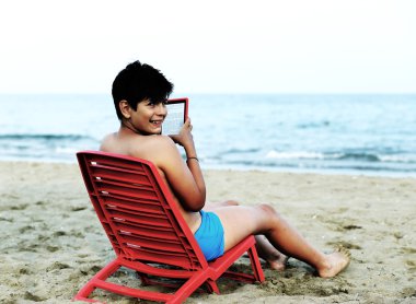 genç çocuk kırmızı sandalye üzerinde bir ebook okur