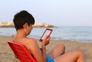 Yalnız çocuk saç siyahlarla bir e-kitap okur