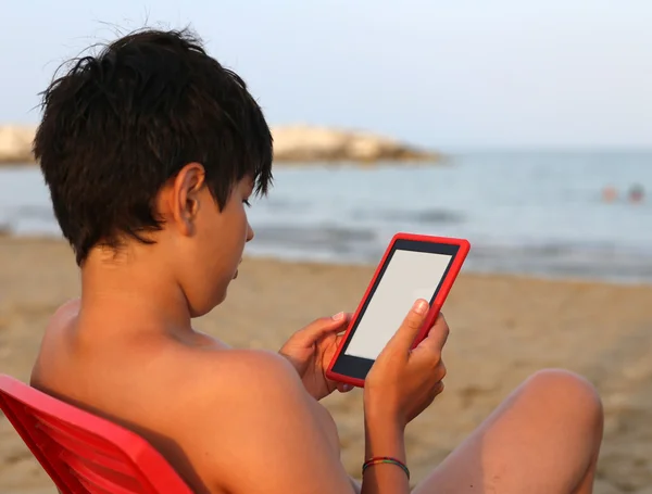 Sam chłopiec z czarnych włosów czyta ebook w lecie — Zdjęcie stockowe