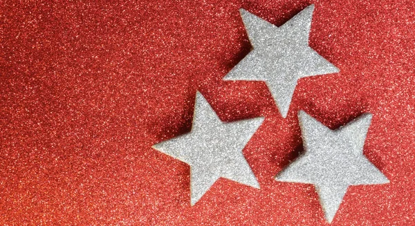 Three silver stars on bright red glittery illuminated background — Stock Photo, Image