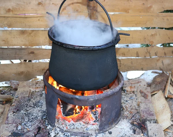 Großer schwarzer Topf mit angezündetem Feuer — Stockfoto