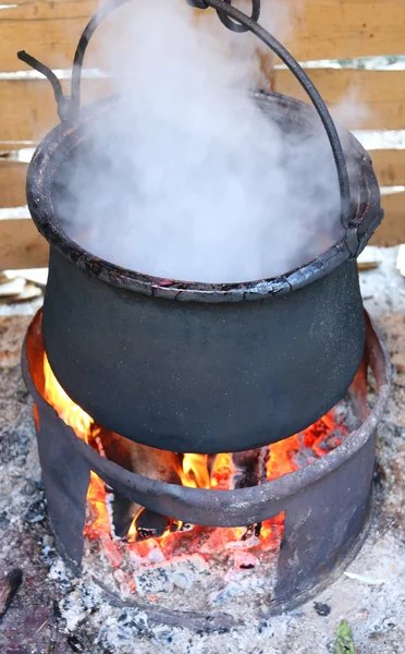 Olla negra con el fuego y el humo durante la cocción — Foto de Stock