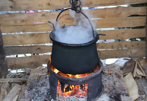 Large pot with the fire lit and the white smoke during cooking — Stock Photo, Image