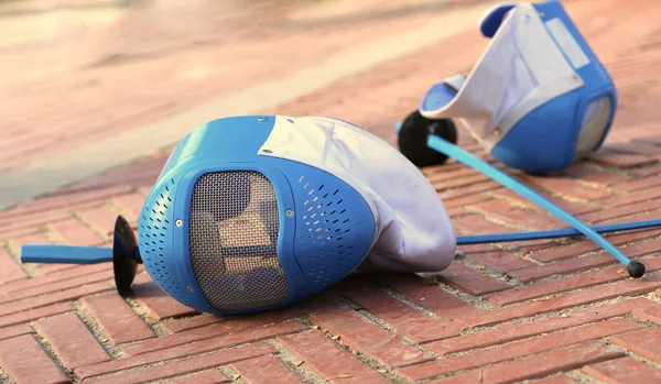 Equipment fencing mask and foil resting on the ground after the — Stock Photo, Image