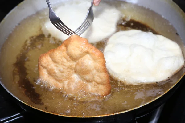 Cocinar los buñuelos fritos grandes sumergidos en aceite caliente en un aluminio — Foto de Stock