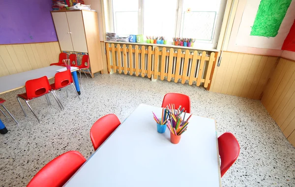 Inside kindergarten with desks and small red chairs — Stock Photo, Image