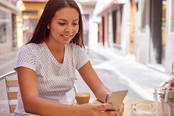 Lykkelig pige smiler til sin mobiltelefon - Stock-foto