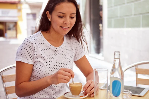 Flot ung brunette omrøring hendes kaffe - Stock-foto