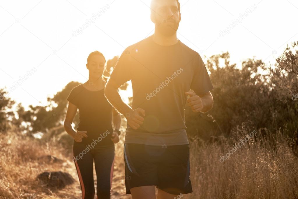 Competitive couple jogging out in nature