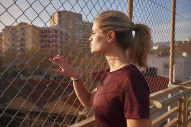 Genç sarışın kadın elini çite doğru kaldırdı ve önündeki tren raylarının manzarasına baktı.