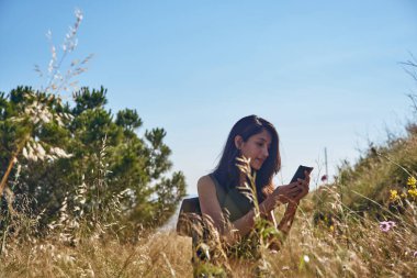 Vahşi doğada, yabani otlar ve çalılarla çevrili bir kadınla mesajlaşıyorum.