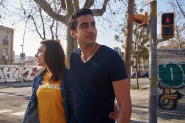 Çekici genç çift, karşıdan karşıya geçerken kol kola yürüyorlar.