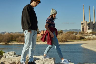 İki zincirsiz genç gün boyunca deniz boyunca kayaların üzerinde yürüyor.