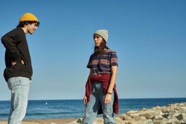 İki havalı genç plaj boyunca kayalıklarda öylece dikiliyor.