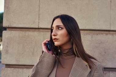 Derin düşüncelere dalmış bir şekilde yan binaya bakan meşgul bir bayan.