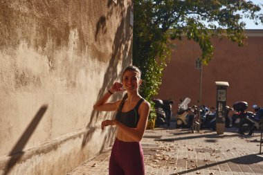 Genç kadın egzersiz yaparken hafifçe gülümseyerek kollarını kaldırır.