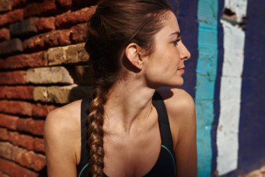 Genç bir kadın başını çevirirken kameraya doğru eğiliyor.