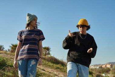 Tepeden aşağı yürüyen ve el hareketleriyle konuşan iki özgür genç insan.