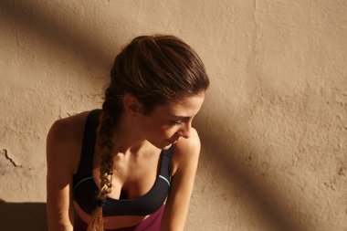 Genç kadın öne eğiliyor ve başını öne eğip aşağıya bakarken yana doğru eğiyor.